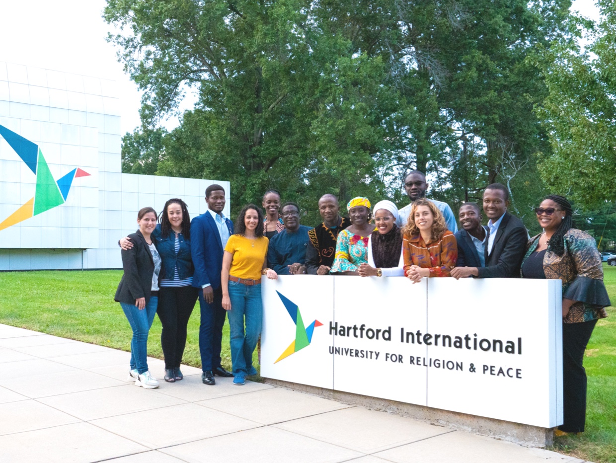 A diverse group of students sitting and standing in front of HIU's main building